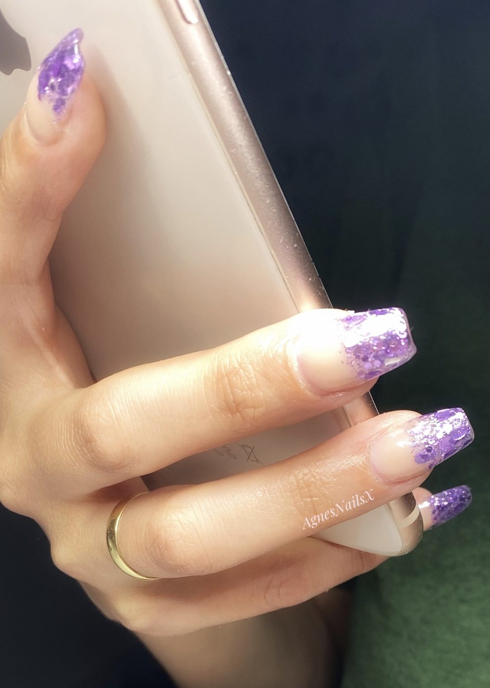 Nagels met paarse glitter French tips, hand om een telefoon